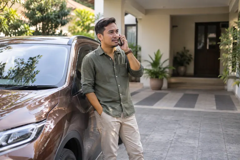 Pelanggan dengan telefon di sebelah kereta yang diparkir